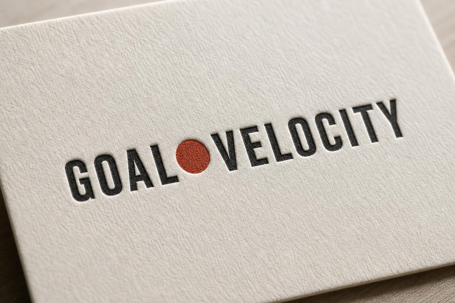 GOAL●VELOCITY wordmark letterpressed on cream cardstock — near-black type with rust-red dot accent